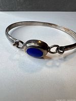 Full view of sterling silver bangle showing blue enamel cabochon and hook clasp