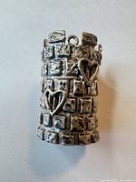 Side view of tower pendant showing brick texture and heart motifs