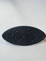 Front view showing ornate floral scroll design and marquise shape