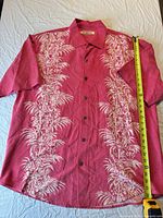 Front view of red silk Hawaiian shirt with measuring tape indicating length