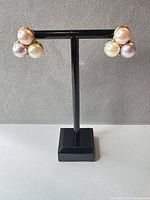 Front view of both Trifari faux pearl cluster earrings on stand