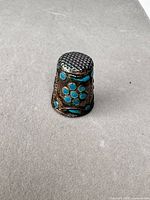 Front view of thimble showing turquoise enamel and patinated metal body