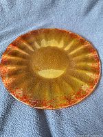 Top view of golden-yellow fused glass plate showing radial pattern and frit texture