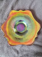 Front of Dugan amethyst carnival glass plate showing iridescent surface and scalloped rim