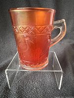 Front view of marigold carnival glass shaving mug on stand