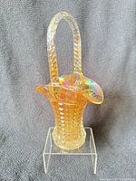 Full view of clambroth carnival glass basket standing on acrylic riser