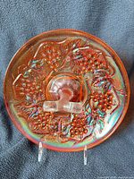 Top view of round marigold carnival glass tray showing Harvest Grapes pattern and iridescence