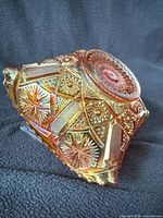 Side view of iridescent marigold carnival glass bowl showing star and file panels