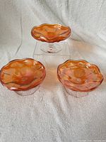 Three marigold carnival glass footed dishes on fabric backdrop, showing tops