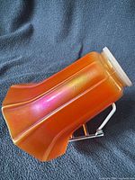 Side view of marigold carnival glass lamp shade showing six-panel flared shape and iridescent surface