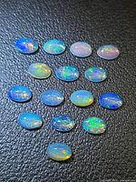 Top view of all oval crystal opal cabochons on black background