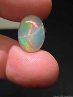 Opal showing play-of-colour on fingertip