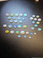 Full layout of all oval opal cabochons on dark surface