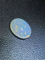 Oblique view of oval cabochon opal showing multicolour play-of-colour