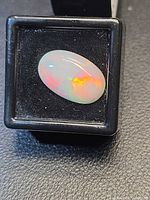 Oval cabochon opal in display case showing play of color