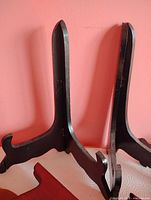 Close-up of two dark wooden folding easels showing hinge and curved feet