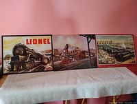 Three tin train signs side by side on table
