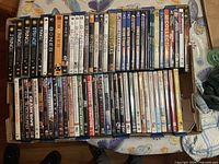 Top view of open cardboard box showing two rows of DVD cases, spine titles legible