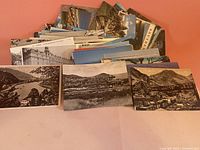 Stack of numerous colour and black-and-white scenic postcards spread out
