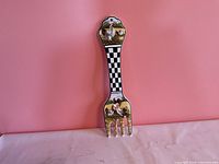 Front view of ceramic wall fork showing chicken artwork and checkerboard handle