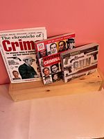 Front view showing all three crime-related hardcover books on wooden stand