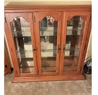 Front view showing three glass doors, wood frame, shelves