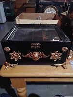 Overall view of closed black box with glass lid and gold appliques
