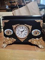 Front view showing clock, gold accents, ship medallions