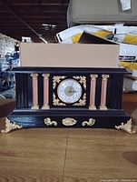 Front view showing clock face, columns and gold decorations