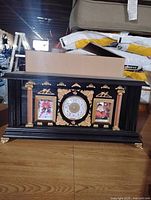Front view showing clock dial, gold columns, photo frames