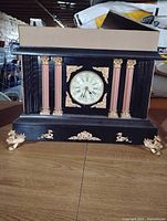 Front view of mantel clock showing dial, columns, and decorative feet