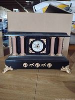 front view of black mantel clock with columns and gold accents
