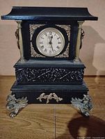 Front view showing clock face, brass-tone columns, ornate bezel, griffin feet