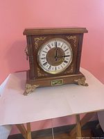 Front view of wood mantel clock showing dial, case, decorative accents