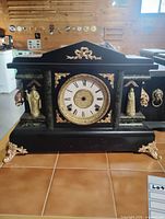 Front view of mantel clock case showing dial, ornaments, overall style