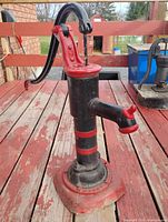 Full view of cast iron hand pump on wooden surface