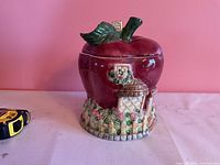 Front view of apple cookie jar showing cottage relief and size reference
