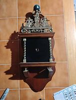 Front view of wood wall clock case with brass crest, columns and shelf