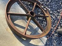 Top view of rusted six-spoke steel wheel on concrete and gravel
