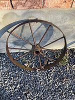 Full view of single steel spoked wheel on gravel background