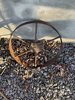 Front view of rusted seven-spoke steel wheel on gravel