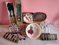 Group shot of entire lot including shot glasses, leaf dish, trivets, Christmas plate, spoons, utensils, candles, copper tray