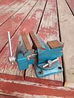 side view of blue bench vise showing swivel base and handle