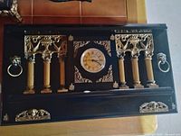 Front view of entire wall clock showing ornate columns, dial, decorations
