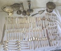 Full lot overview showing flatware, candlesticks, basket, bowl