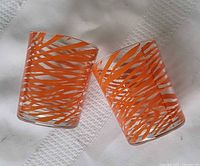 Both orange swirl glasses lying on cloth showing external pattern