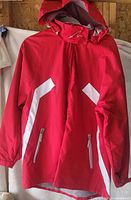 Front view of red Alpinetek jacket showing white panels and zippered pockets