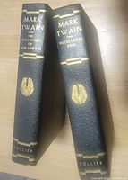 Spine view of both hardcovers showing titles, author, emblem and publisher