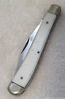 Knife closed showing imitation pearl handle and bolsters