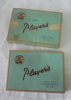 Top view of both tins showing logos, tape residue, wear